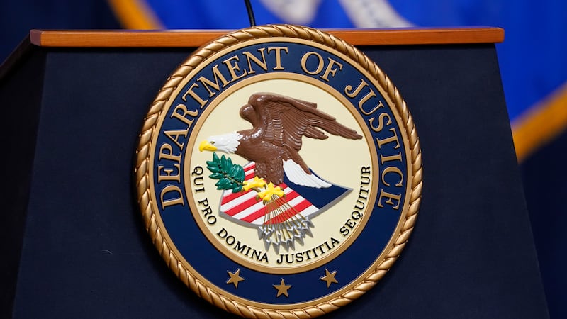 The seal for the United States Department of Justice is displayed on a lectern before a news...