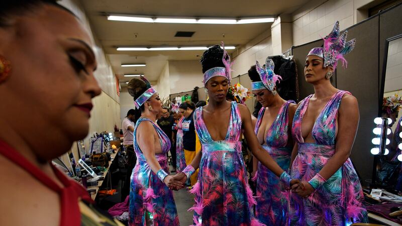 Performers, including Chevis Regal, center, hold hands before performing in the Mahu Magic...