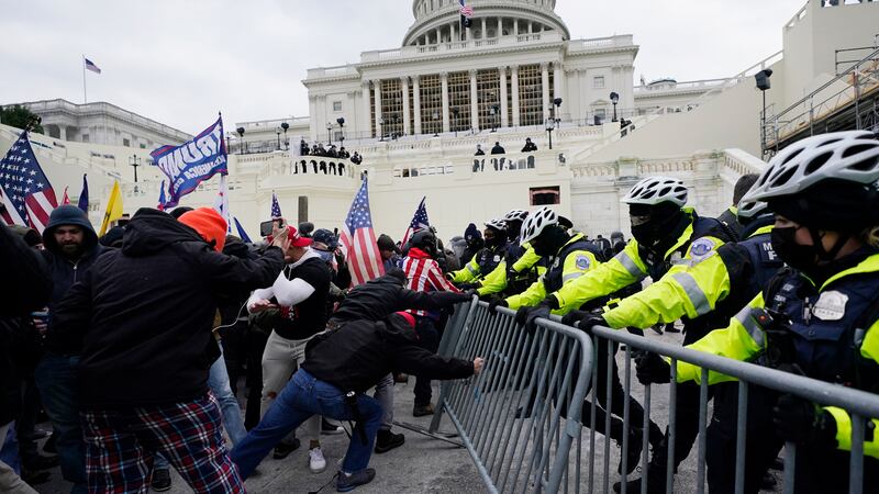 FILE - Rioters loyal to President Donald Trump try to break through a police barrier,...
