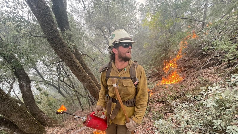 A Tahoe National Forest Truckee Hotshot uses a drip torch to conduct planned tactical firing...