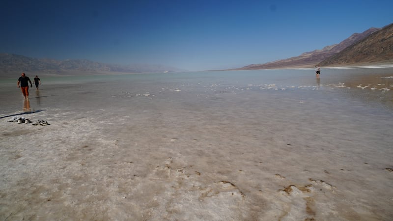 Park visitors wading in the temporary lake at Badwater Basin